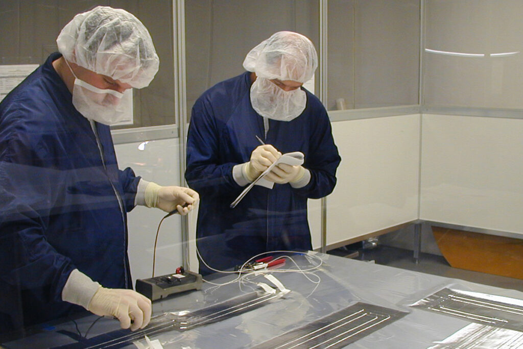 Two laboratory workers in lab with clean room gear on.
